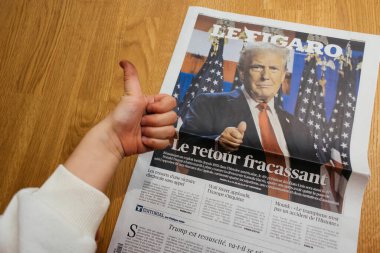 Paris, Fransa - 7 Kasım 2024: Meraklı çocuk Le Figaro gazetesinde Donald Trump 'ın siyasi dönüşüyle ilgili başparmak kaldırıyor, dünya haberlerine erken ilgi gösteriyor