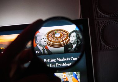 Paris, Fransa - 6 Kasım 2024: ABD seçim yayınları sırasında televizyon ekranında tutulan büyüteç, Donald Trump, Kamala Harris ve yüksek bahisleri sembolize eden bir rulet tekerleği görüntüleri