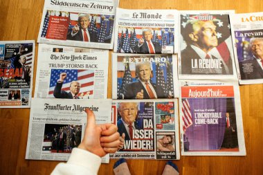Paris, Fransa - 7 Kasım 2024: Çok sayıda uluslararası gazete Trump 'ın seçim geri dönüşünü ön planda çocuk okuyucu onayıyla ahşap bir zeminde sergiliyor