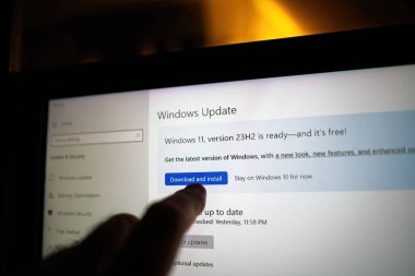 Paris, Fransa - Sep 10, 2024: Bir dizüstü bilgisayardaki Windows Güncelleme ekranına parmak işareti, Windows 11 sürüm 23H2 için indirme ve yükleme düğmesini vurguluyor, güncellemeye hazır.