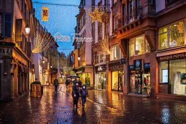 Strasbourg, Fransa - 4 Aralık 2020: Noel pazar sezonunda Strazburg Petite France bölgesinin akşam manzarası, şenlikli ışıklar, dekorasyonlar ve kaldırımlar ıslak bir kaldırım taşı caddesinde.