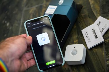 Paris, Fransa - 14 Kasım 2020: Bir Philips hareket sensörü akıllı telefon ile bağlanıyor, akıllı ev otomasyonunu ve yakınlardaki paketleme ve paketleme ile kolay kurulumu gösteriyor - paketleri açıyor