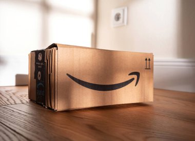 Paris, Fransa - 14 Kasım 2020: Ahşap bir zeminde Amazon Prime teslimat kutusu, e-ticaret ambalajlarını ve kapalı mekan ışıklarında tanınan Amazon logosunu gösteriyor