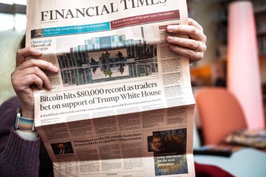 Paris, Fransa - 13 Kasım 2024: Elleri Financial Times gazetesinde Bitcoin 'in 80.000 ABD Doları' nı vurması ve Donald Trump 'ın seçim sonrası ekonomik nüfuzunu konu alan manşetler tutuyordu.