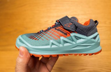 Berlin, Germany - Apr 13, 2024: A close-up of a vibrant Lowa hiking shoe, featuring a sturdy turquoise sole and modern orange detailing, highlighting its premium outdoor design clipart