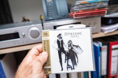 Paris, Fransa - 31 Ekim 2024: Fleetwood Mac SACD 'sini arka planda çok sayıda SACD' nin de bulunduğu, ön planda birinci sınıf müzik sergilenen, sembolik bir Fleetwood Mac SACD 'sini tutan bir erkeğin POV çekimi