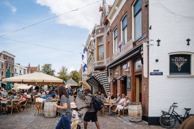 Alkmaar, Hollanda - 30 Ağustos 2024: Ons Bistro - t Kantoor Orta Alkmaar 'da insanların terasta eğlenerek yerel halkın cazibesini yakaladığı geleneksel Hollanda mimarisini sergiliyor