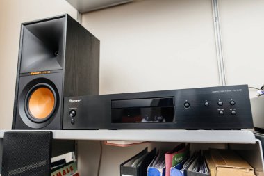 Paris, France - Dec 21, 2024: Overhead shot of a Pioneer compact disc player paired with Klipsch Reference speakers, placed on wooden shelves in a stylish audiophile room setup clipart