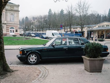 Baden-Baden, Almanya - 1 Aralık 2024: Baden-Baden 'de bir caddeye park edilmiş şık Bentley, tarihi mimari, yeşillik ve lüks ve kibarlığı ön plana çıkaran hareketli bir şehir zemin