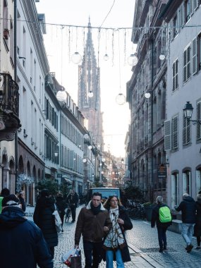 Strasbourg, France - Nov 29, 2024: Street view of Strasbourg during the Christmas market, featuring festive decorations, shoppers, and the iconic Strasbourg Cathedral in the background, creating a clipart