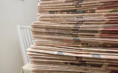 Uzun iş gazeteleri düzgünce bir masaya dizilmiş, basılı makaleler ve manşetler sergileniyor.