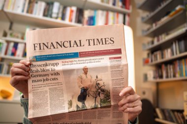 Paris, France - Dec 9, 2024: Person holding Financial Times with headlines on Thyssenkrupp job cuts in Germany and a controversial pro-Russia figure, Calin Georgescu, in Romanian politics clipart