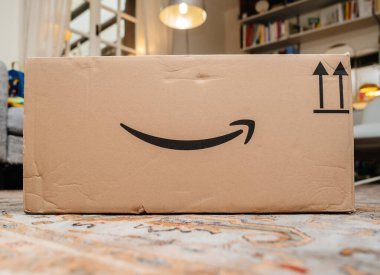 Paris, Fransa - 1 Aralık 2024: İkonik gülümseme logosunun yer aldığı büyük bir Amazon kutusu, kapalı bir yere yerleştirilmiş, sergilenen teslimat, lojistik ve markalı ambalaj
