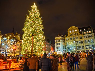 Strasbourg, France - Dec 23, 2023: A glowing Christmas tree at the Strasbourg annual Christmas market, surrounded by festive buildings and visitors, capturing the spirit of the holiday season clipart