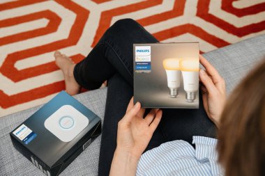 Paris, Fransa - 16 Ağustos 2019: Bir Philips Hue köprüsünü ve akıllı ampulleri açarken modern desenli halı ile sıcak, sade bir ortam sunan kadın manzarası