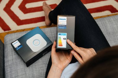 Paris, Fransa - 16 Ağustos 2019: Philips Tue akıllı ampul paketinin enerji etiketini vurgulayan bir kadın, enerji verimliliği ve sürdürülebilirlik bilgilerine odaklanıyor.