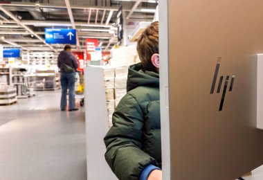Paris, Fransa - 14 Aralık 2024: Bir çocuk, IKEA 'daki büyük bir HP ekranıyla etkileşime geçerek, müşteriler arka planda gezinirken etkileşimli bir oturuma katılıyor.