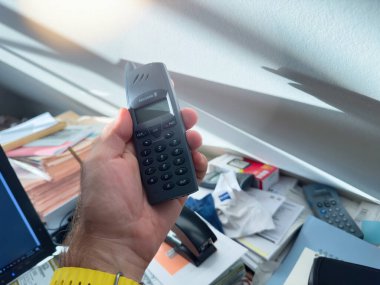 Paris, France - Sep 14, 2024: Handheld Ericsson DT290 dect cordless phone shown in a workspace setting, emphasizing its sleek design and classic keypad layout. clipart