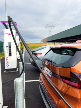 Paris, Fransa - 28 Kasım 2024: Bulutlu bir günde bir yalnızlık istasyonunda BMW iX1 elektrikli SUV şarjı, temiz enerji ve sürdürülebilir otomotiv yeniliklerini vurguluyor.