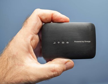 Paris, Fransa - 1 Aralık 2024: Kablosuz bağlantı için tasarlanmış, portakallı mobil WiFi cihazı, sinyal ve pil göstergeleri.