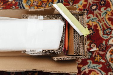 Yatak çerçevesi bileşenleri koruyucu köpük ve malzeme katmanlarıyla dolu bir karton kutuda güvenli bir şekilde paketlenir, nakliye için canlı halı kaplı bir yüzeye yerleştirilir..