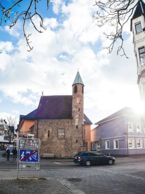 Achern, Almanya - 3 Ocak 2025: Achern, Almanya 'da bir ortaçağ tarzı kilise, parlak bir gökyüzünün altında trafik işaretleri ve yakındaki kentsel binalarla çevrili bir taş kule yer alıyor..