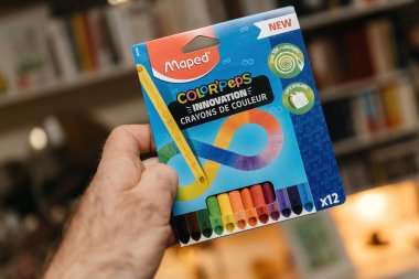 Paris, Fransa - 28 Aralık 2024: Maped Color 'Peps marka renkli renkli pastel boyaları tutan bir el, yenilikçi tasarım ve renkli ambalajlar sergileniyor..