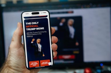 Paris, Fransa - 20 Ocak 2025: Bir akıllı telefon ekranında Trump 'ın bulanık arka planına sahip bir açılış gününde resmi Trump mim için bir reklam yayınlanıyor