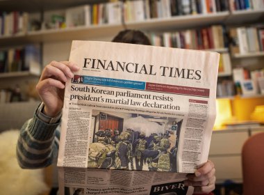 Paris, Fransa - 9 Aralık 2024: Financial Times 'ı okuyan bir kişi, Güney Kore parlamentosunun cumhurbaşkanının sıkıyönetim ilanına karşı koyduğunu ve sıcak bir ev ortamında hazırlandığını manşet attı.