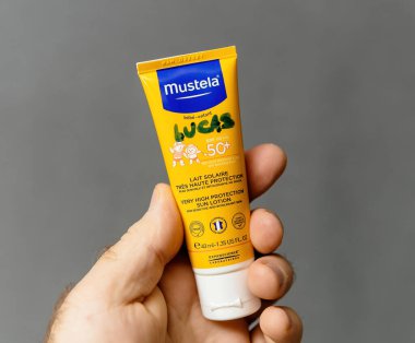 Paris, Fransa - 18 Ocak 2025: Bebek ve çocuklar için bir tüp Mustela güneş losyonu tutan bir el, 50 'den fazla, hassas cilt için tasarlanmış UV ışınlarına karşı çok yüksek korumalı.