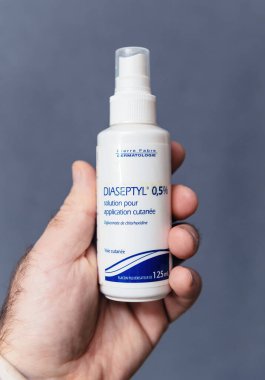 Paris, France - Jan 18, 2025: A hand holding a 125 mL bottle of Diaseptyl 0.5percent, a chlorhexidine-based antiseptic solution for skin application, designed for wound care and hygiene. clipart