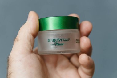 Paris, France - Jan 18, 2025: A hand holding a Romanian Gerovital Plant moisturizing cream jar with natural plant extracts, designed to hydrate and nourish the skin while maintaining a healthy glow clipart