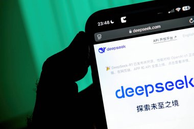 Paris, Fransa - 28 Ocak 2025: Çince DeepSeek web sitesini gösteren akıllı telefon ekranı, logo ve metin, yeşil ışıklı arka planda cihazı tutan bir el ile