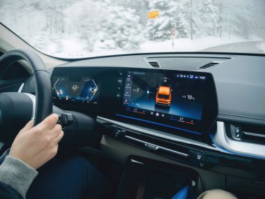 Kara Orman, Almanya - 3 Ocak 2025: Karlı ve donmuş koşullarda sürülen bir BMW iX1 elektrikli arabanın iç görünümü, dijital gösterge paneli ve modern denetimleri gösteriyor