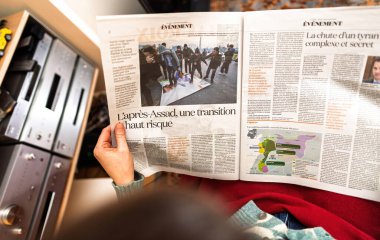 Paris, Fransa - 9 Aralık 2024: Suriye 'nin Esad sonrası sorunlarını analiz eden bir gazete makalesi, bir kişi tarafından açık tutuldu ve yerel bir ortamda raporlar ve çizelgeler sunuldu.