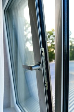 Açık modern bir pencere. Açık havada metalik sapı ve temiz cam panelleri var. Havalandırma ve doğal ışığı vurguluyor..