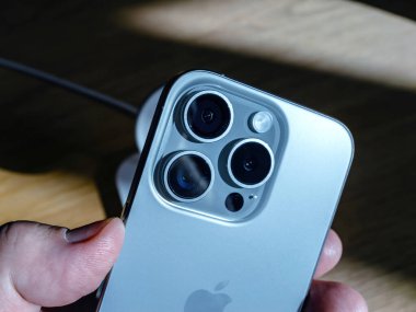 Paris, Fransa - Sep 22, 2023: Bir iPhone 'un kamera lenslerinin detaylı yakın görüntüsü, gümüş bir gövdedeki bulanık ahşap arka plan üzerindeki üçlü lens sisteminin hassasiyetini vurguluyor.