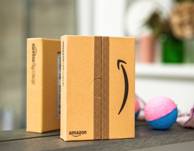 Paris, Fransa - 22 Kasım 2021: Yansıtıcı bir yüzey üzerinde yansıtan iki Amazon hediye kartı kutusu, parlak renkli toplar ve arka planda bulanık bir dekor, hediye odaklı bir temayı vurguluyor.