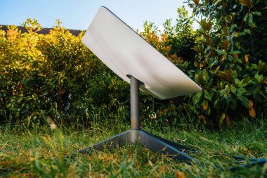 Frankfurt, Almanya - 15 Haziran 2023: SpaceX tarafından bir Starlink uydu anten, yumuşak doğal ışık altında yemyeşil yeşilliklerle çevrili, çimenli bir çimenliğe kurulmuştur..