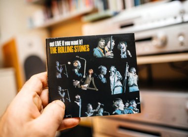 Paris, Fransa - 10 Aralık 2025: Rolling Stones canlı SACD albüm kapağında arka planda ses ekipmanı ve performans fotoğraflarının yer almasını istiyorsanız, erkek eli Rolling Stones 'un LIVE albümünün kapağını tutuyor.