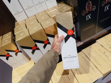 Paris, Fransa - 30 Aralık 2024: Moet ve Chandon Brut İmparatorluğu Şampanya Kutusu 'nu tutan bir el, aynı marka altın ve beyaz ambalajlarla çevrili bir mağazada.