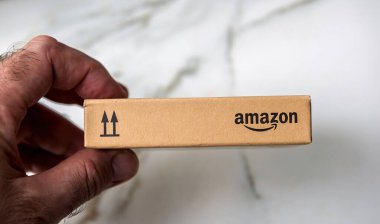 Paris, Fransa - 22 Kasım 2021: Yukarı doğru ok sembolü olan, ambalaj detaylarını gösteren, Amazon damgalı küçük bir karton paketi tutan bir elin yakın çekimi.