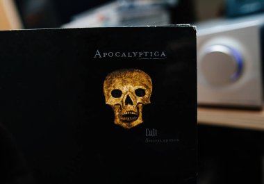 Paris, Fransa - 10 Aralık 2024: Apocalyptica 'nın Tarikat Özel Sürümü CD kapağı, arka planda bulanık bir ses düğmesi bulunan altın kafatası tasarımı