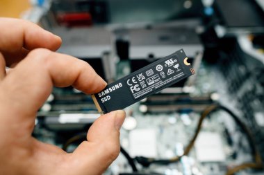 Paris, Fransa - 15 Haziran 2023: Bir el Samsung NVMe SSD 'yi görünür iç bileşenleri olan açık bir bilgisayar çantasının üzerinde tutuyor, güncelleme veya kuruluma hazırlanıyor.