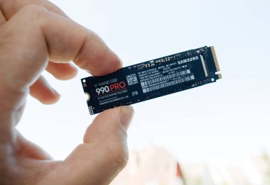 Paris, Fransa - 15 Haziran 2023: Bir el Samsung 990 Pro NVMe SSD 'yi 2TB kapasiteli, PCIe 4.0 teknolojili, çatıları bulanık bir açık hava arka planına karşı tutuyor.
