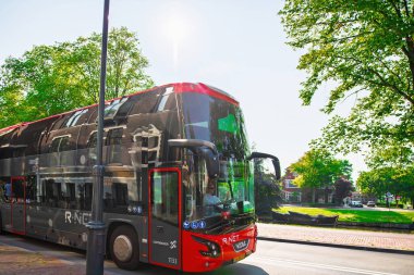 Haarlem. Hollanda - 26 Ağustos 2019: Yansıtıcı camları olan şık çift katlı bir R-NET otobüsü Haarlem 'de, üzerinde tarihi binalar bulunan ağaçlarla kaplı bir caddeden geçiyor.