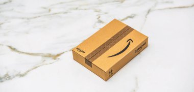 Paris, Fransa - 22 Kasım 2022: İmza siyah bantlı küçük Amazon markalı karton bir paket çevrimiçi alışveriş ve e-ticaret teslimatını temsil eden beyaz mermer bir yüzeye yerleştirildi.