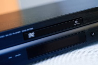 Frankfurt, Almanya - 15 Haziran 2023: Yumuşak ışıklandırma altında hafif tozlu bir yüzeye sahip disk tepsisi, markalaşma ve ön panel düğmelerinin yer aldığı bir Super Audio CD ve DVD oynatıcısının yakın çekimi.