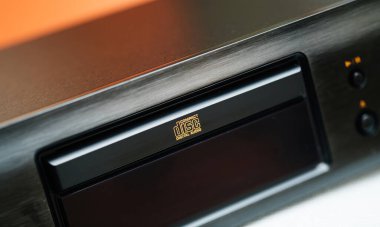 Üst düzey bir çalgıcının tepsisindeki kompakt disk dijital ses logosunun yakın plan görüntüsü, fırçalanmış metal kaplama ve aydınlatılmış kontrol düğmeleri.