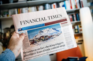 Frankfurt, Almanya - 22 Ocak 2025: Bir kişi, Grönland 'ın manzaralı karla kaplı bir köy imajının yer aldığı siyasi ve ekonomik konularla ilgili manşetlerin yer aldığı bir Financial Times gazetesi tutuyor.
